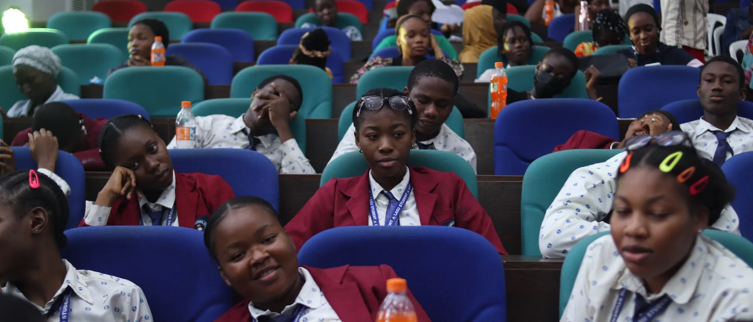 Students in school blazers filling a lecture hall.