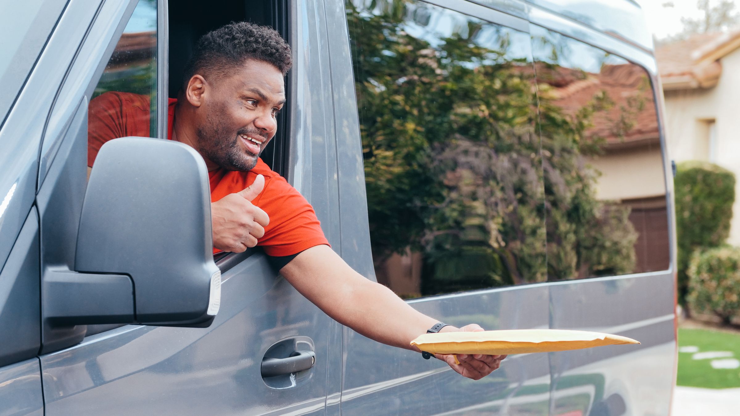 Courier handing a parcel out of a delivery van