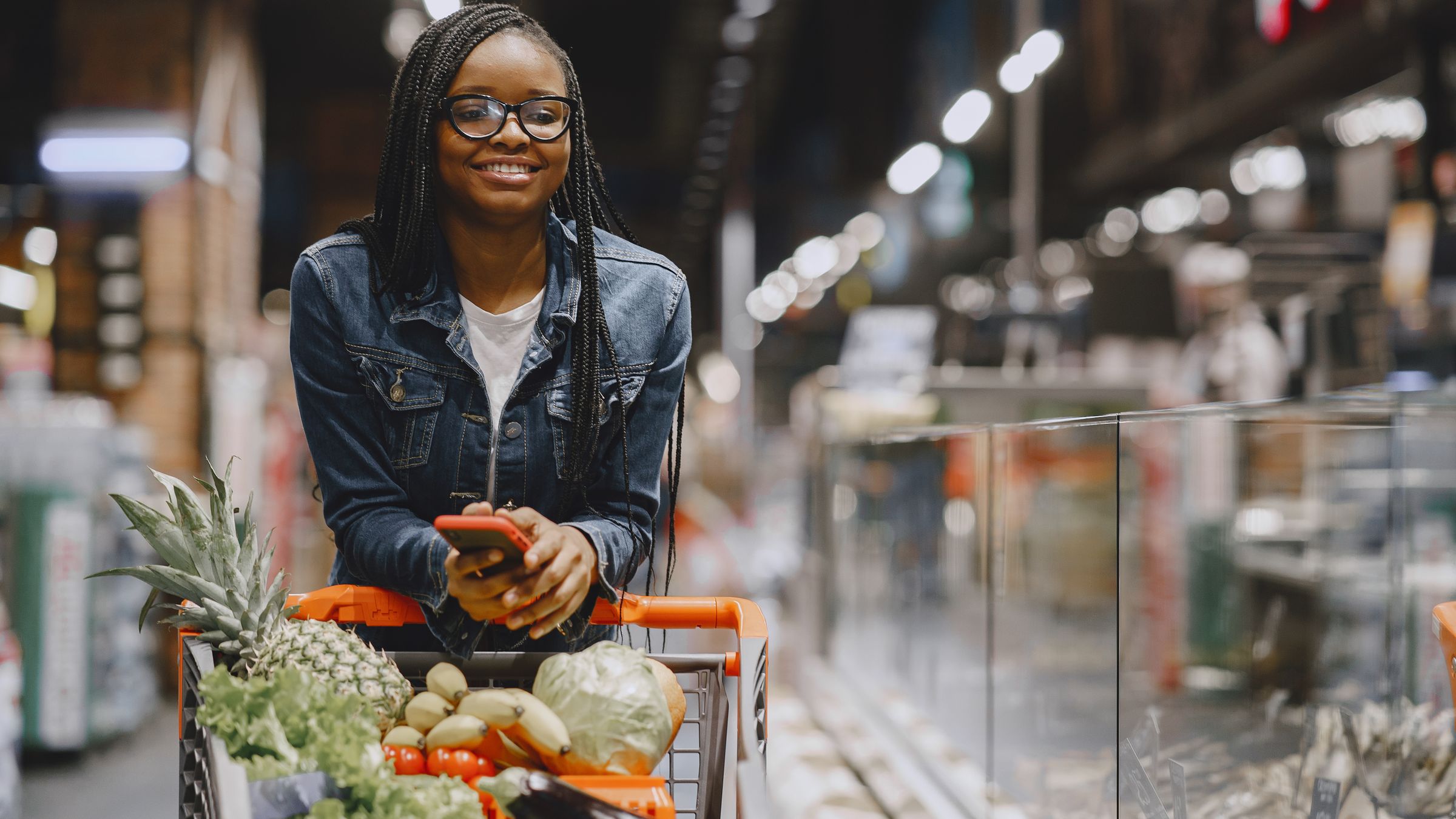Shopper with a trolley checking her phone in a supermarket